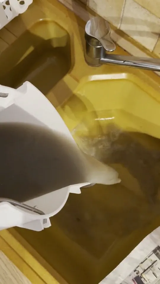 L'eau brune ressortie du nettoyage d'un matelas à Voiron, versée dans un évier